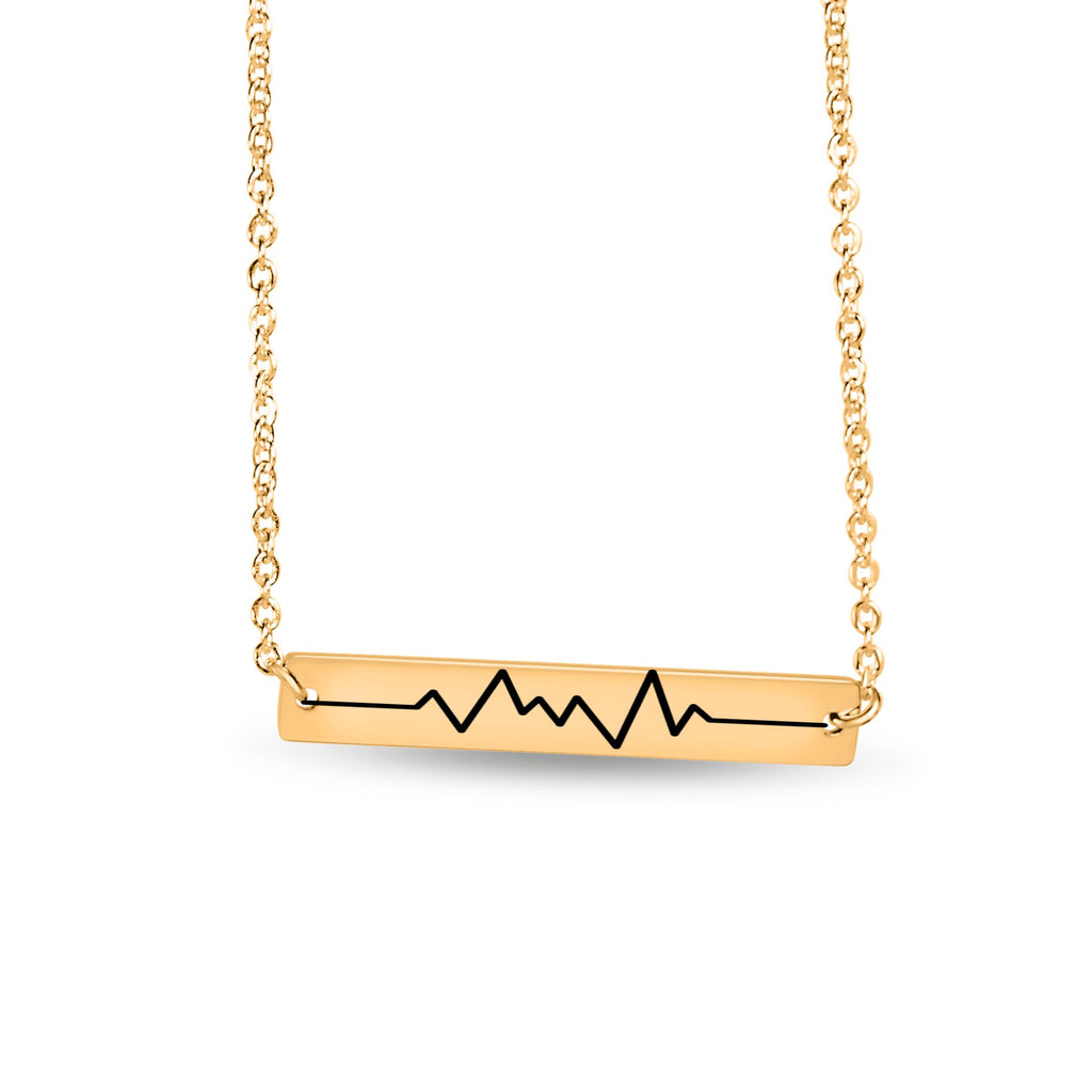 Vergoldete Halskette mit einem horizontalen Bar‑Anhänger, der einen gravierten Baby‑Herzschlag‑CTG‑Verlauf zeigt minimalistisch freigestellt fotografiert.