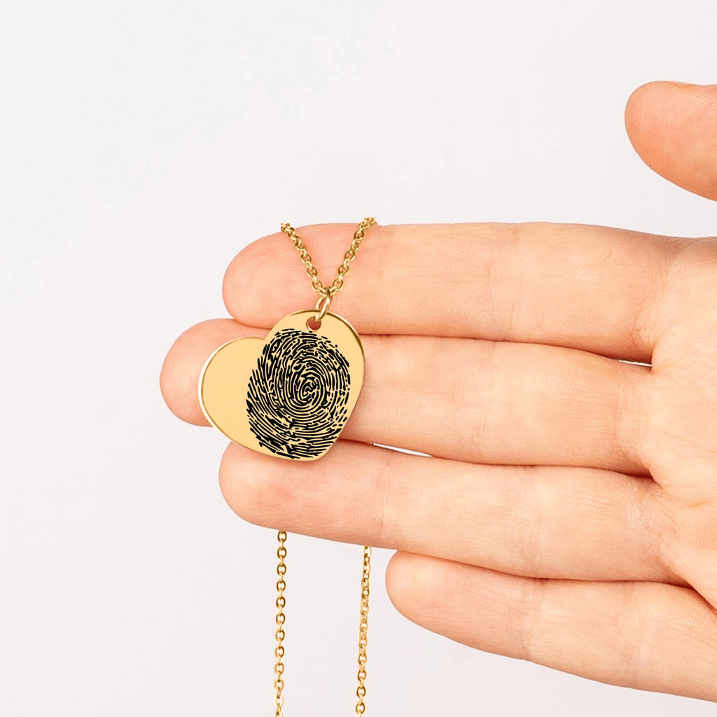 Vergoldete Halskette mit herzförmigem Anhänger und eingraviertem Fingerabdruck, getragen über einem weißen Shirt als personalisierter Schmuck